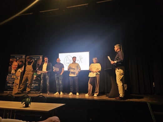 Deelnemers op het podium met de host