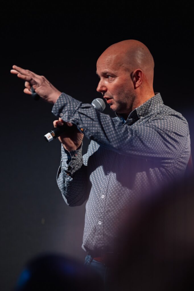 man met microfoon en blauw overhemd